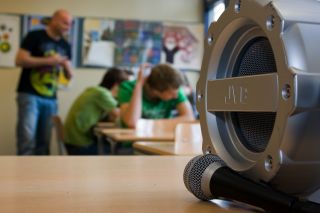 Online muzieksymposium - deel camera met in de achtergrond kinderen in klaslokaal